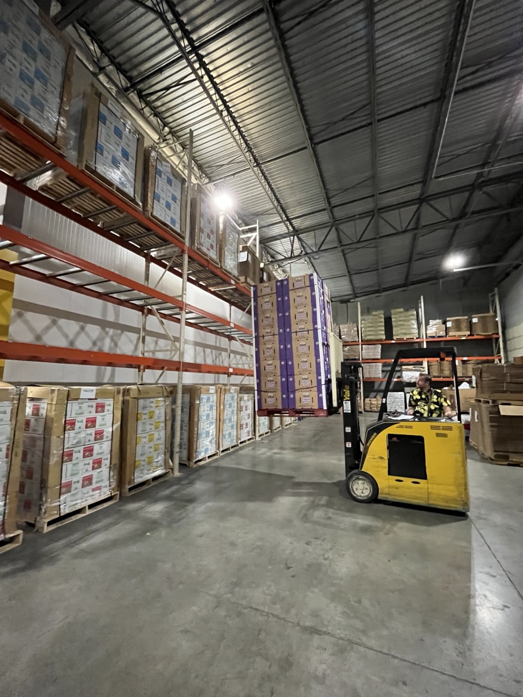 A forklift moving pallets of food through Cascadia's Auburn warehouse